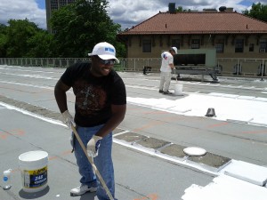 Photo Credit: Carina Nieves A Building and Grounds employee and ConEd representative take part in coating the roof of King Hall 