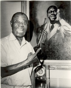 PHOTO COURTESY OF LOUIS ARMSTRONG HOUSE MUSEUM Louis Armstrong, a legendary jazz musician, poses next to a painting of him. 